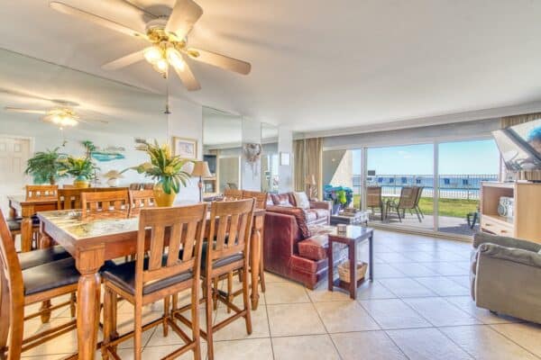 Spacious living room in C104 at the Beach House Condominiums with dining area and patio offering ocean views.