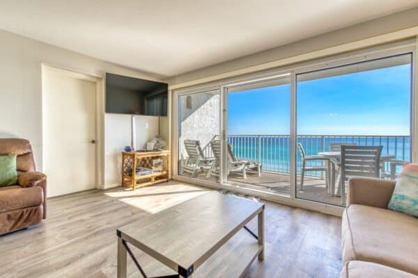 Living room with ocean view through large glass doors, featuring a chair, sofa, coffee table, and patio seating.