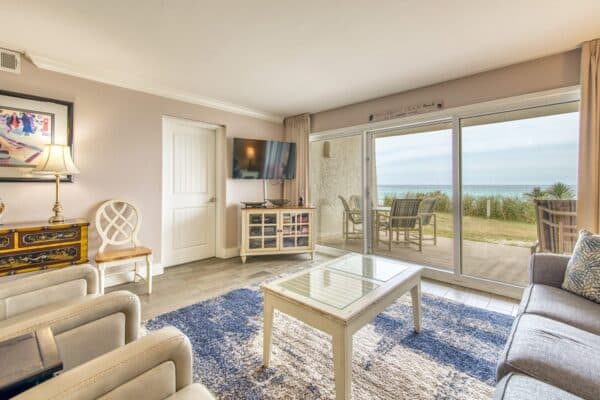Coastal-themed living room in The Beach House Condos with a B101 view through sliding glass doors.
