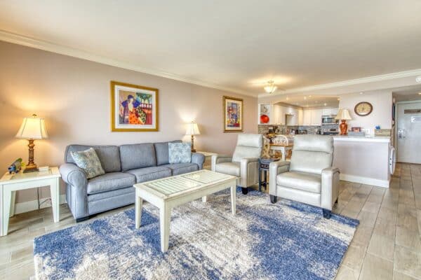 Bright, inviting living room with modern sofa, colorful wall art, and open kitchen at The Beach House Condominiums.