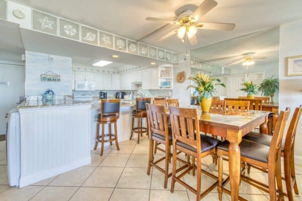 Bright, beach-themed C104 kitchen at The Beach House with bar seats and dining table.