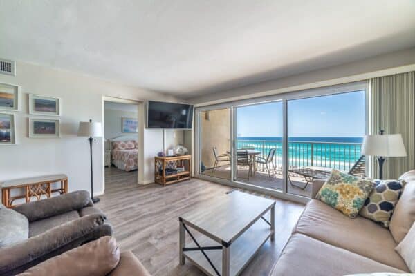 Bright B402 beachfront lounge at The Beach House Condos with sliding doors opening to an ocean-view balcony.