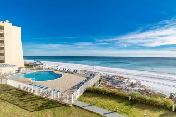 Beachfront condominium with a pool overlooking the beach and ocean under a clear sky.