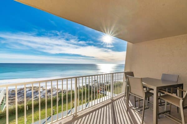Ocean view from the balcony at The Beach House Condominiums, with outdoor furniture and a clear sky.