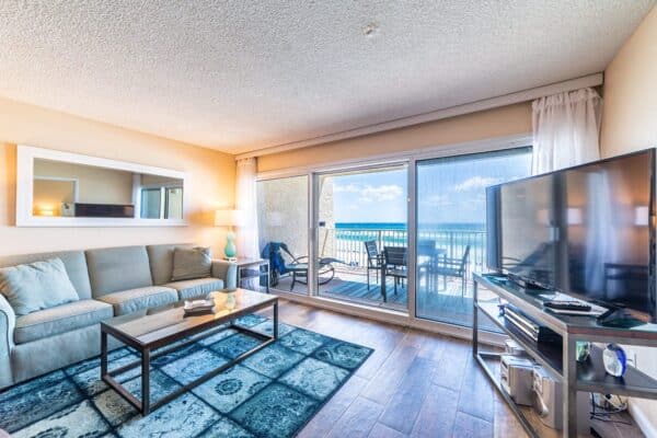 or the condo complex.

Bright living room with a sofa, TV, and ocean-view balcony at a condo complex.