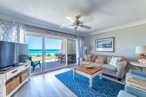 Coastal-themed living room in condominium with beach view through sliding glass doors.