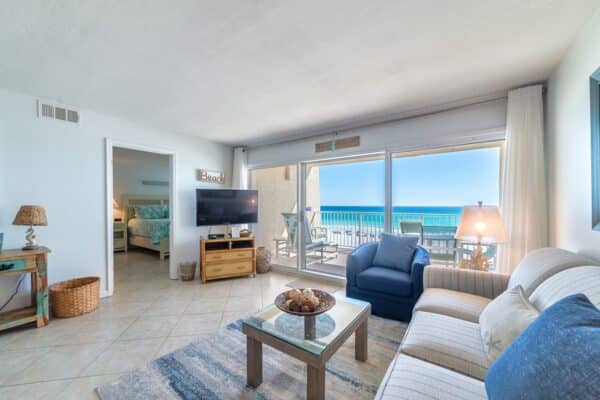 Bright beachfront living area at The Beach House with ocean view, furnished comfortably, leads to D201 balcony.