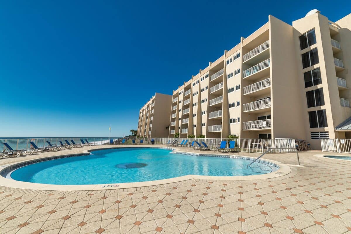 Full view of the large swimming pool at Beach House Condominiums, with the beach and Gulf of Mexico in the distance.