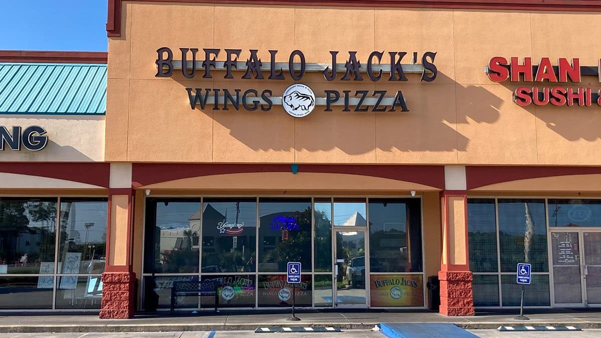 Buffalo Jack's Wings & Pizza" next to "Shan Sushi" at The Beach House Condominiums under a clear blue sky.