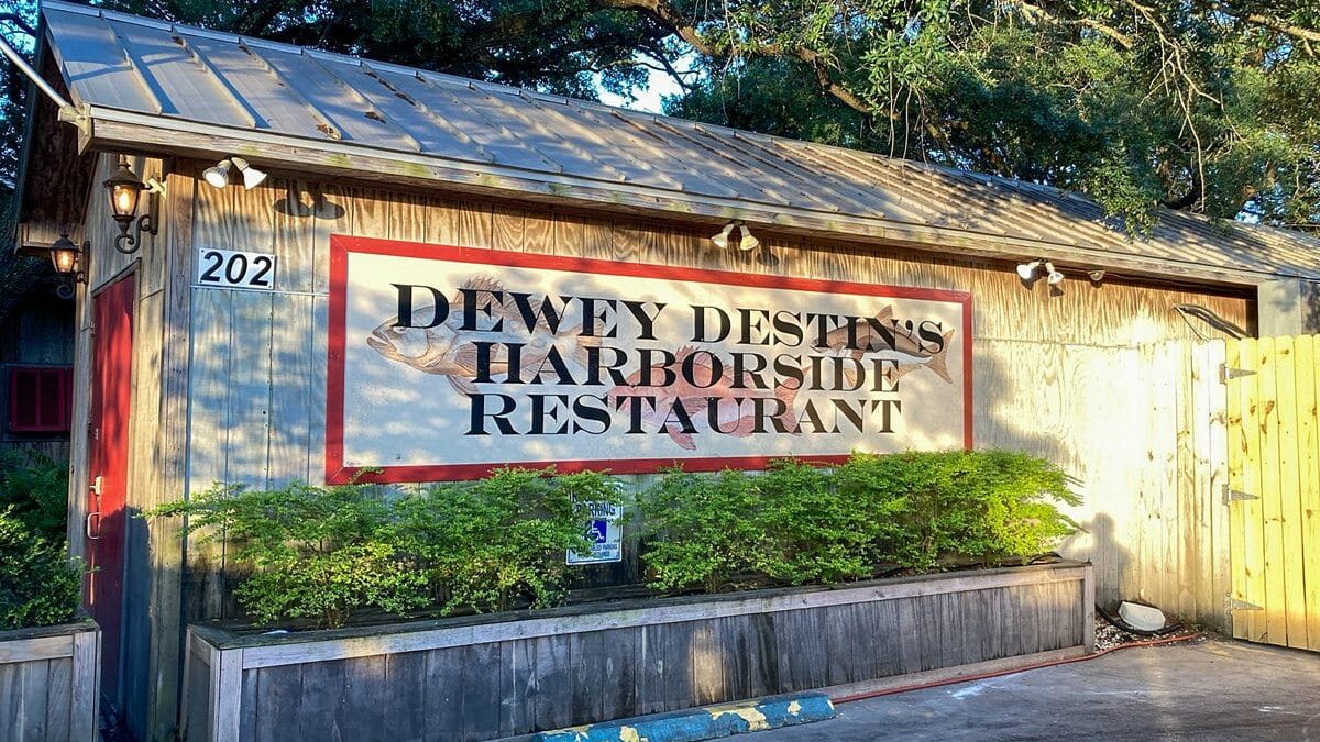 Exterior view of Dewey Destin's harborside restaurant with a bold sign at The Beach House Condominiums.