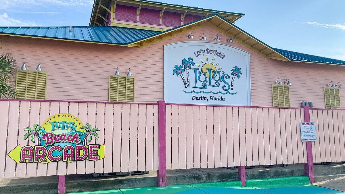 Lulu's beach arcade with a vibrant facade and pink wooden fence at The Beach House Condominiums, Destin.