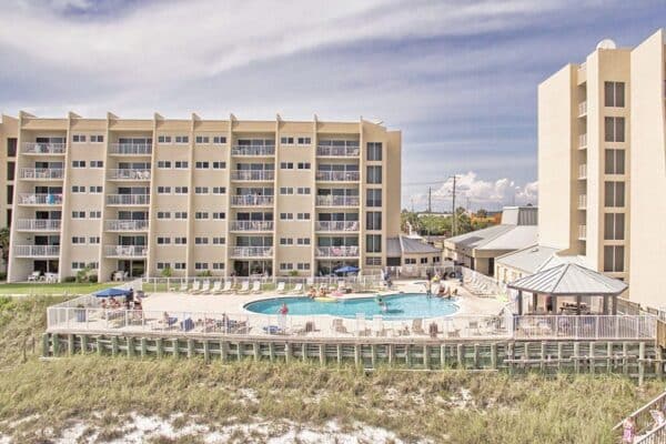 Beachfront condo complex with pool and sunbathers enjoying the sunshine.
