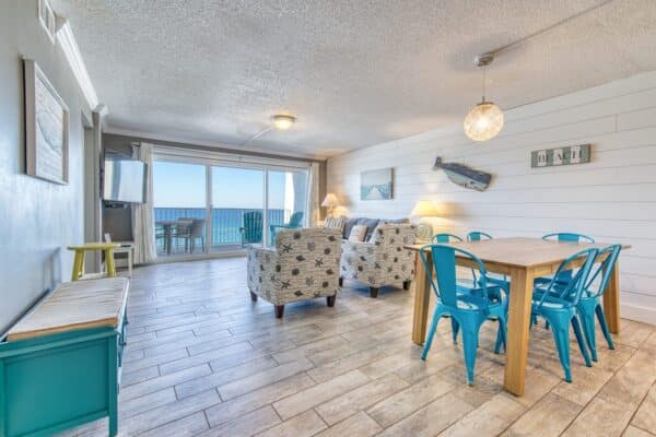 Beach House Condominium B502 interior with ocean view, coastal decor, and open-plan living-dining area.